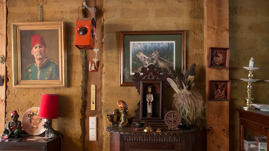 A brick wall is cluttered with antiques, including a painting of two kangaroos.