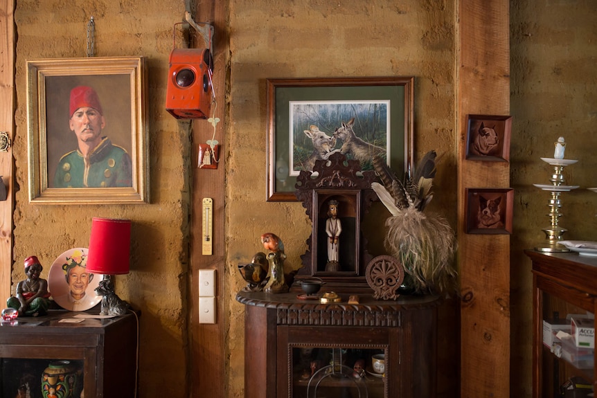 A brick wall is cluttered with antiques, including a painting of two kangaroos.