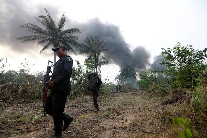 Policemen patrol close to a site used for illegal refining.