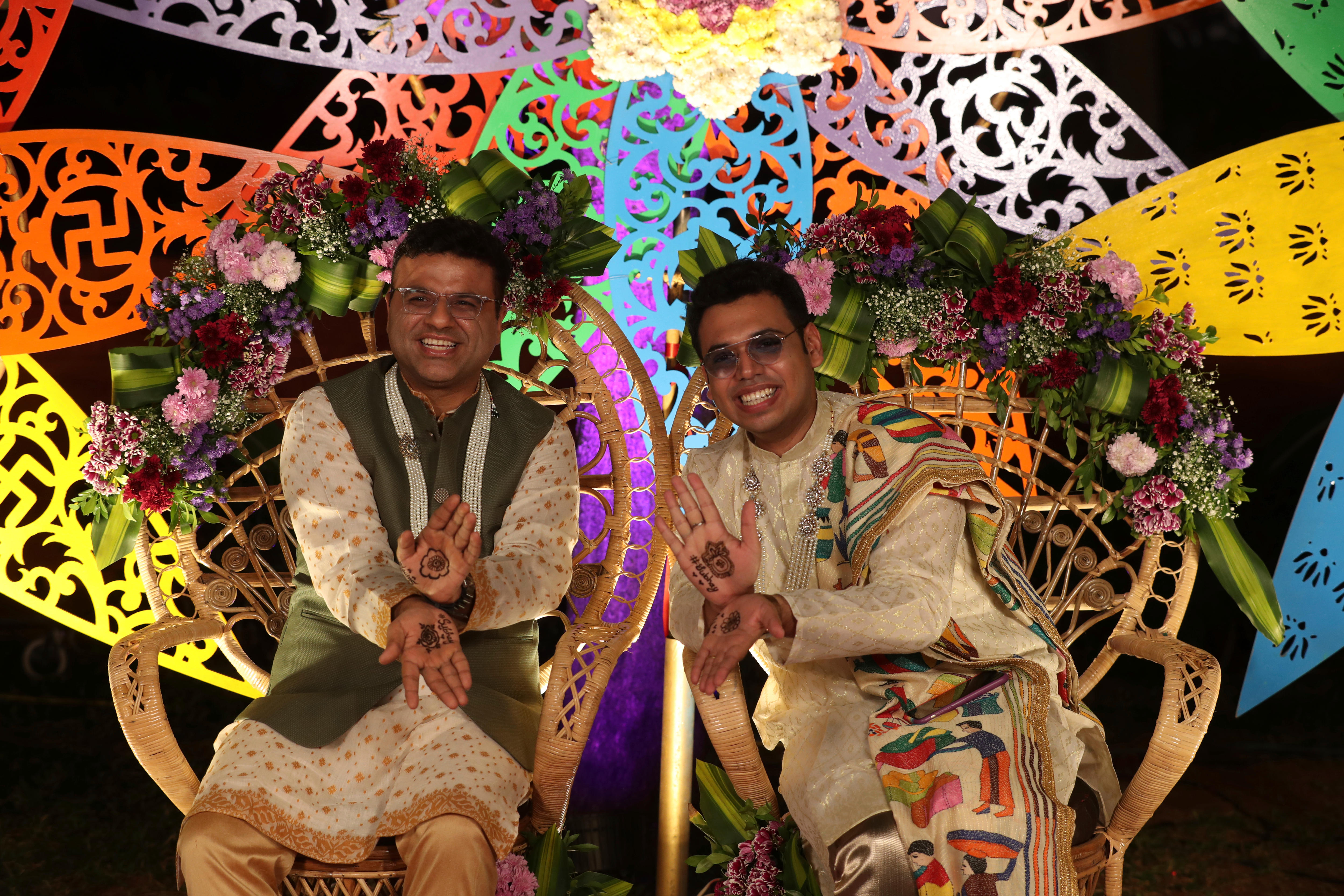 Two men in traditional Indian dress sit next to each other as part of a same-sex marriage union. 