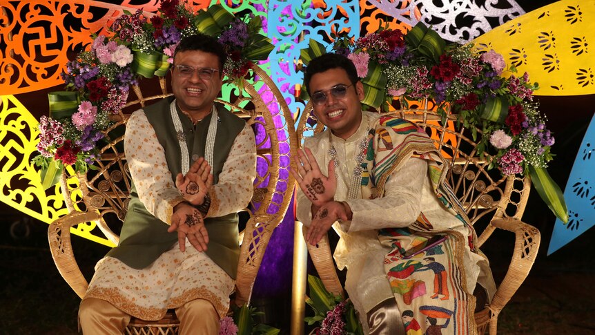 Two men in traditional Indian dress sit next to each other as part of a same-sex marriage union. 