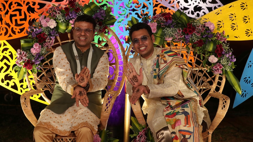 Two men in traditional Indian dress sit next to each other as part of a same-sex marriage union. 
