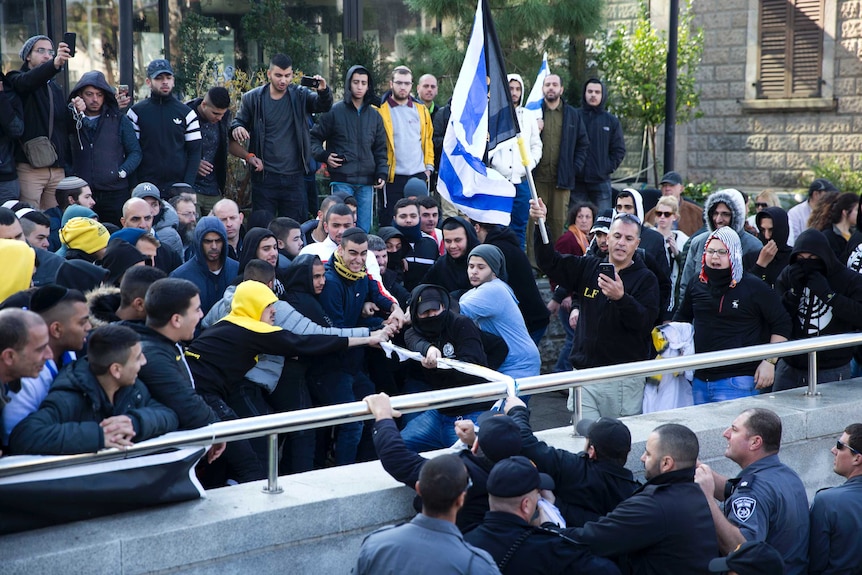 A crowd of protestors pull an Israeli flag outside court.