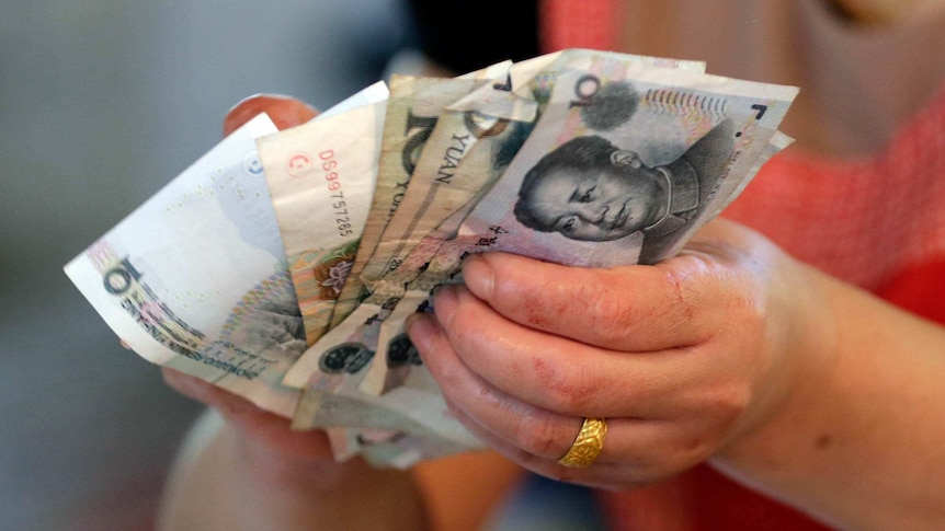 A vendor holds Chinese Yuan notes at a market in Beijing