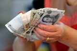 A vendor holds Chinese Yuan notes at a market in Beijing