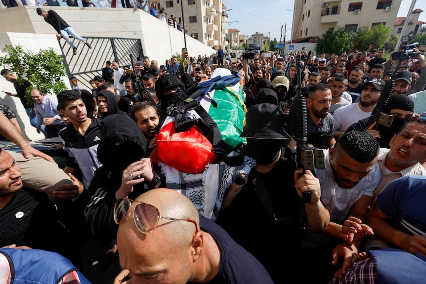 Uzbrojeni napastnicy niosą ciało korespondenta Al-Jazeery, Shireen Abu Akleh