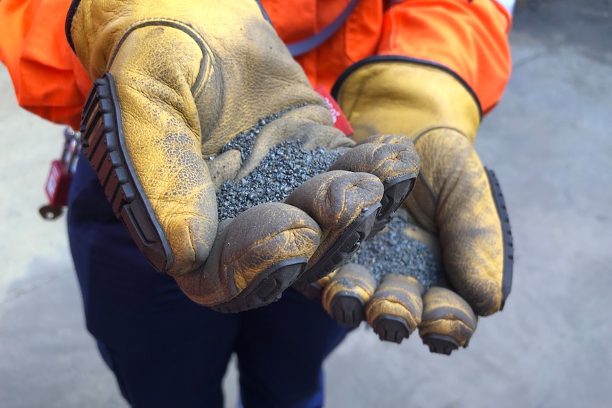 A person holds a handful of ground nickel.