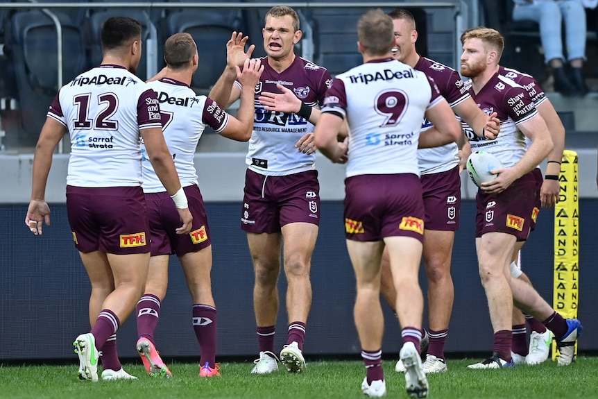 A group of Manly NRL players congratulate each other following a try.