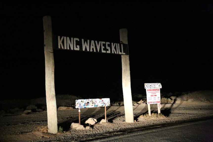 A picture of a King Waves Kill sign on a dark road