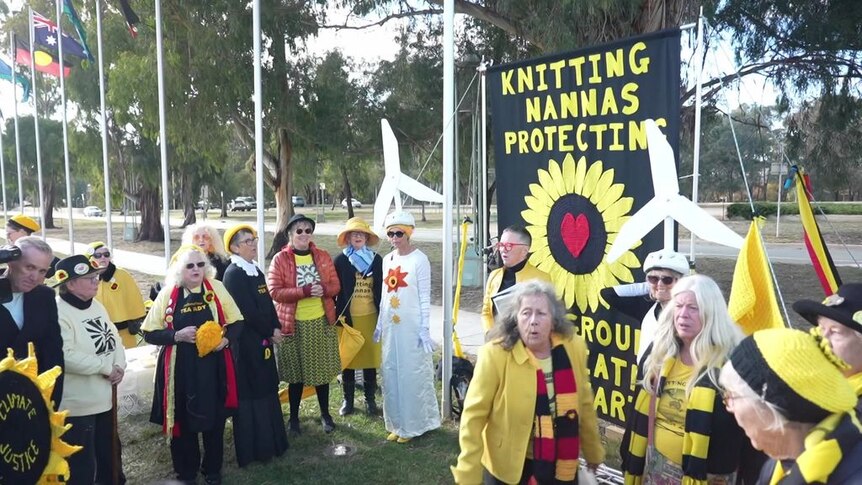 A group of woman dressed in yellow, black and red at a protest.
