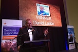 David Larkin standing behind a microphone and lantern speaking.
