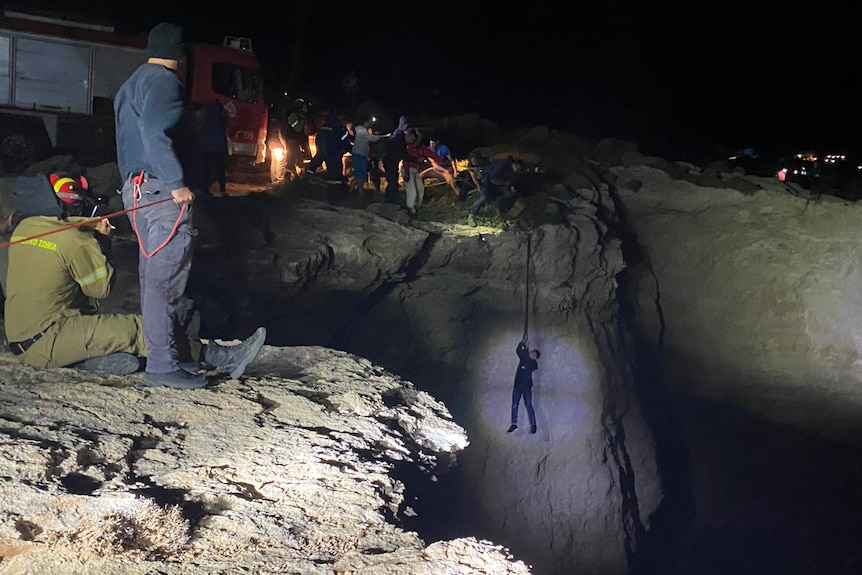 I soccorritori guardano un collega mentre scende da una corda da una parete rocciosa