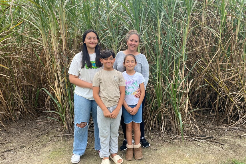 Montana, Dominic and Leilani Nikua with mum Karinna standing in front of a cane field at Karinda Anderson's cane farm in Calen