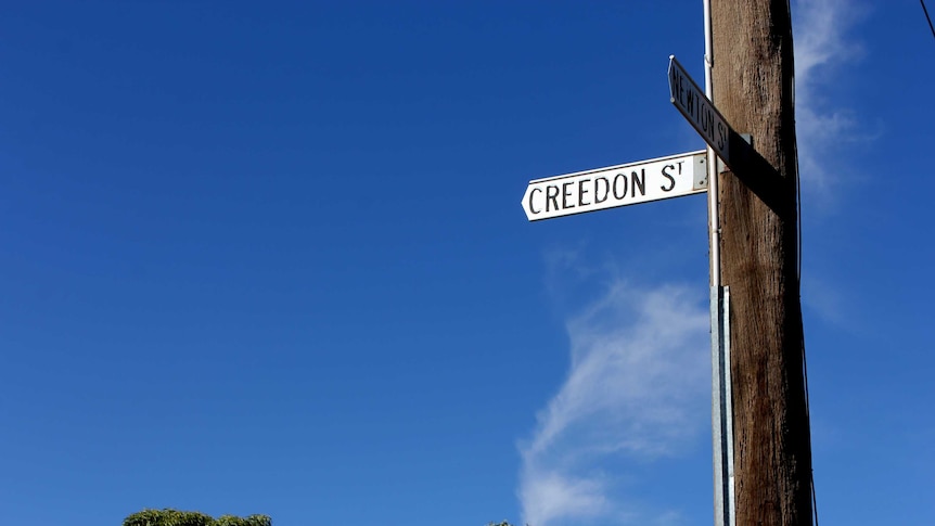 A street sign attached to a power pole, with a blue sky in the background.