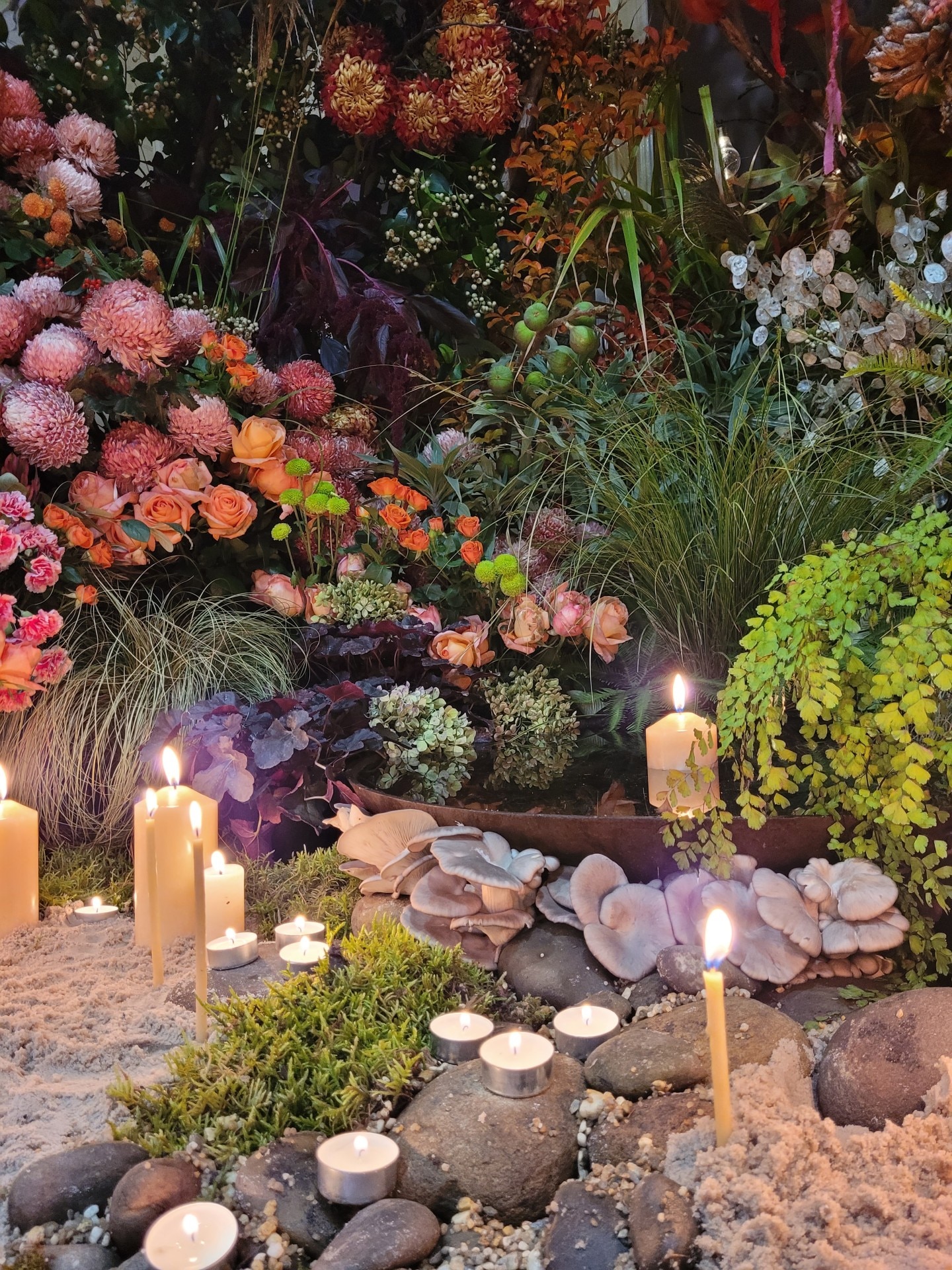 Detail showing flowers, rocks, candles, moss and fungi.