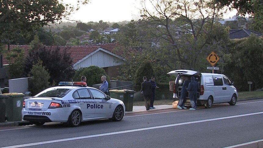 A police car, police officers and forensics officers stand on the road outside a house in Mount Pleasant.