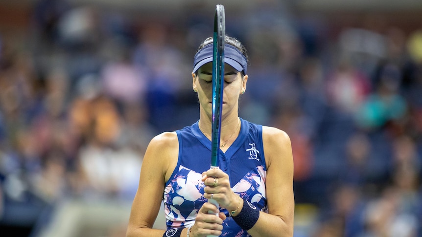 Ajla Tomljanovic holds a tennis racquet up to her her face and closes her eyes during a match at the US Open.