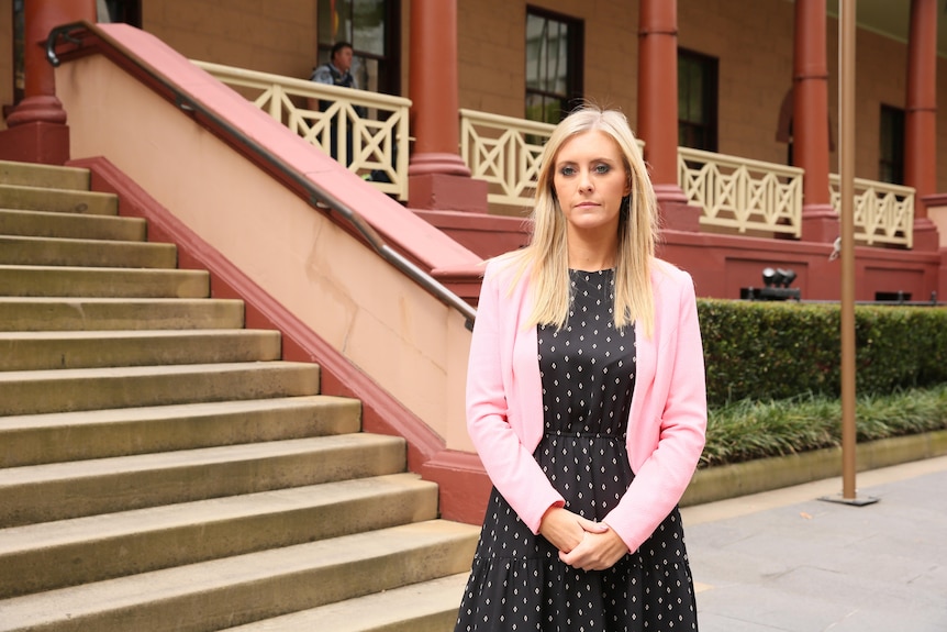 A blonde woman standing outside a government building.