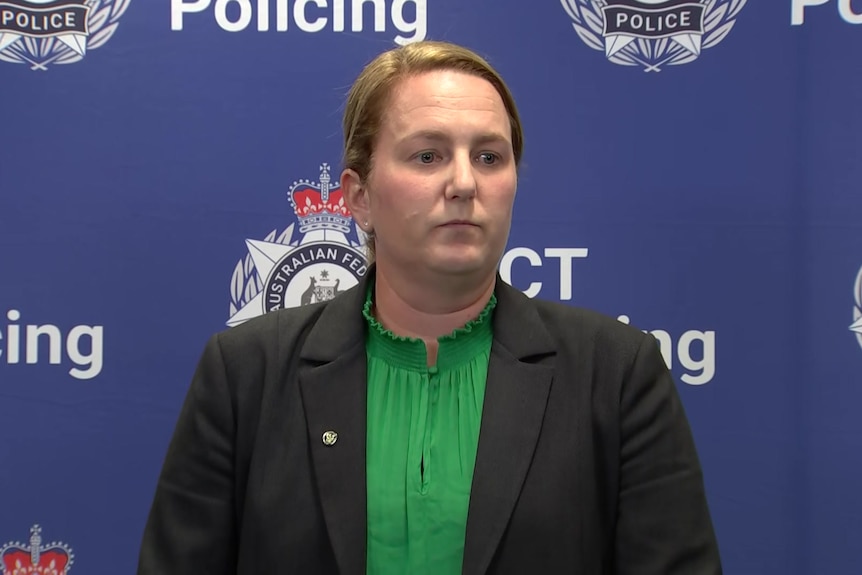A woman looks serious in front of a background that reads "ACT Policing".