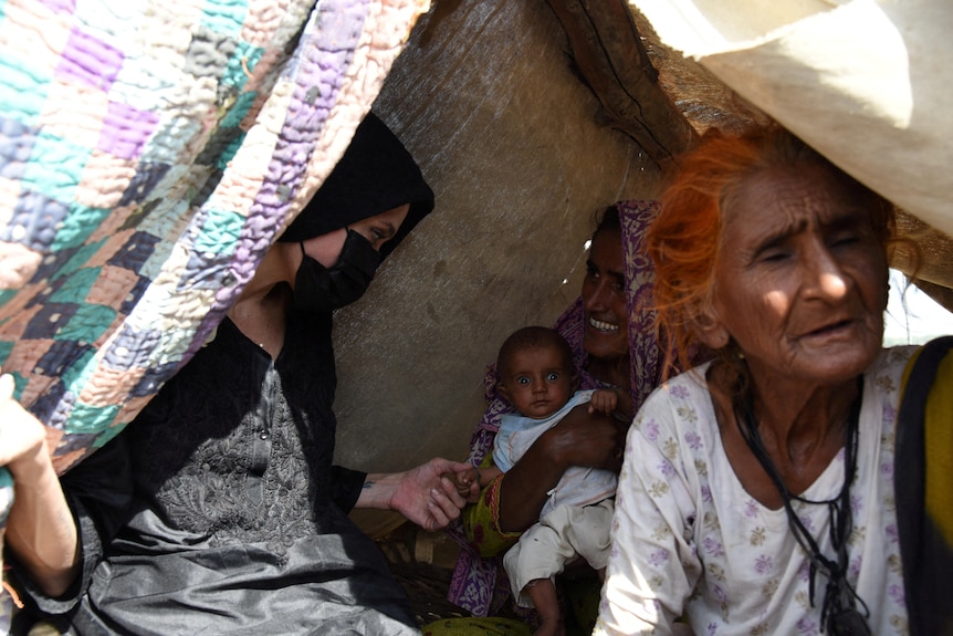 picture of three women chatting with one carrying an infant baby 