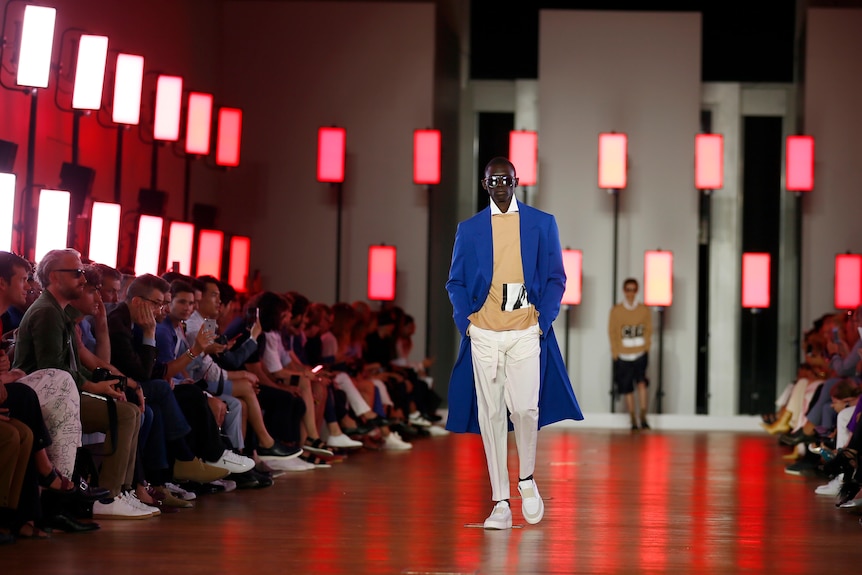 a man walk down a fashion runway in a suit