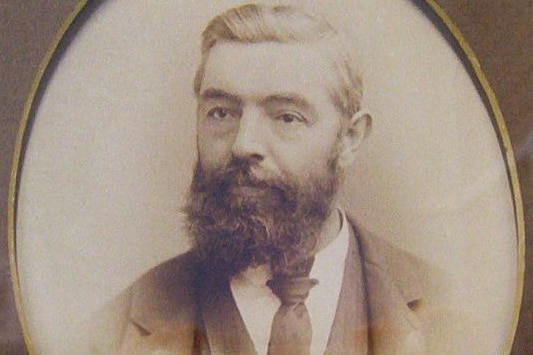 a black and white portrait photo of a man with a beard in a suit 