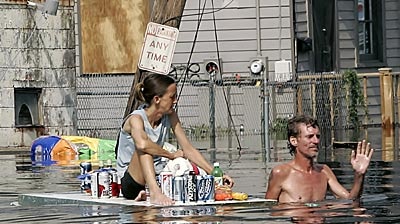 A man, dragging a woman on a floating door with supplies, waves off a rescue boat in New Orleans.