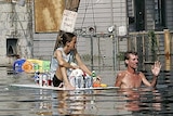 A man, dragging a woman on a floating door with supplies, waves off a rescue boat in New Orleans.