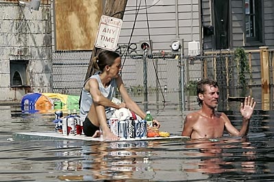 A man, dragging a woman on a floating door with supplies, waves off a rescue boat in New Orleans.