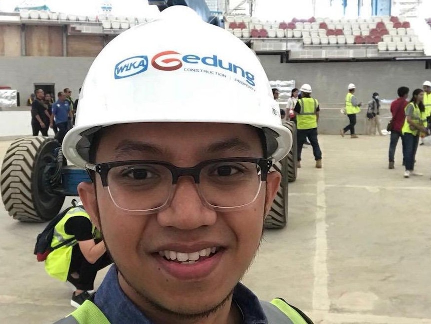 Aulia Rifqiandono wears a hard hat in a construction area.