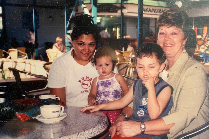 Amishah on her mother's lap, left, at a table with her brother on her grandmother's lap, right.