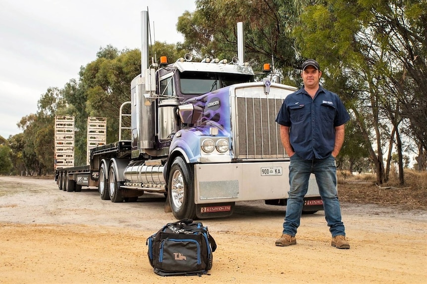Man standing in front of a truck with hands in his pockets.