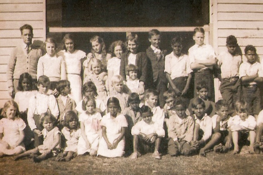 A sepia toned class photo taken in 1935 of 36 students and teacher in front of Baryulgil School.