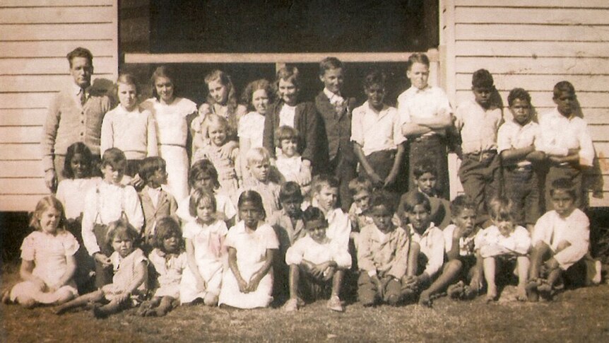 A sepia toned class photo taken in 1935 of 36 students and teacher in front of Baryulgil School.