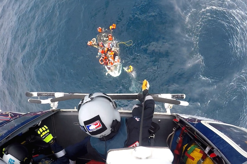 Crew from a helicopter looking down at people in a sinking boat
