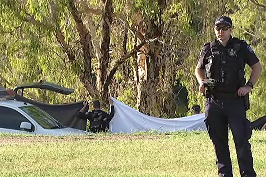 Police officers hold up sheets at the bank of the Ross River in Townsville.