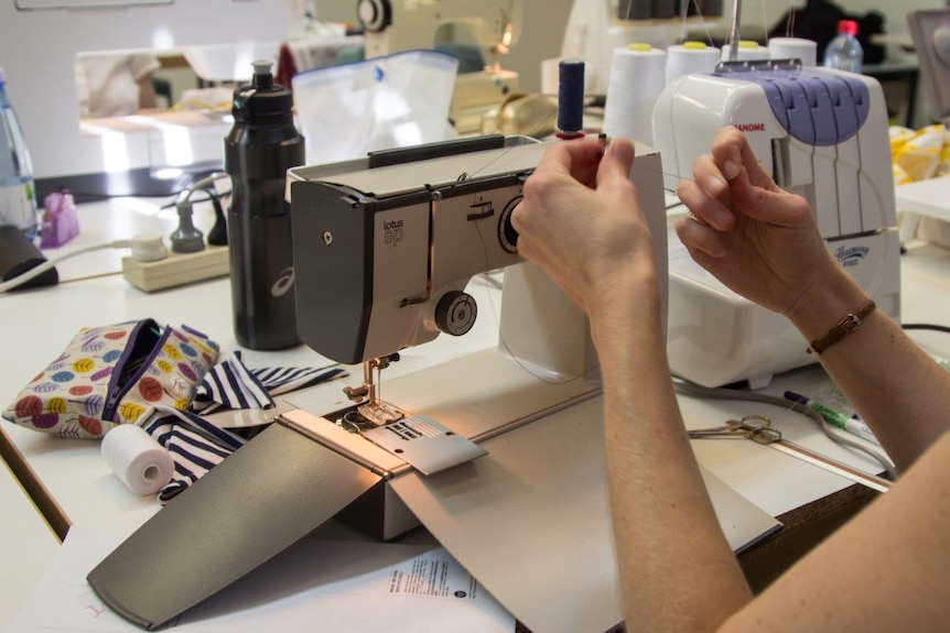 Hands thread a sewing machine