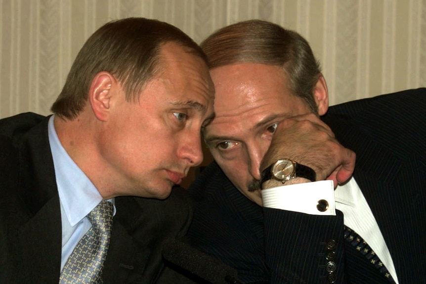 Putin and Lukashenko gently resting their heads together as they whisper