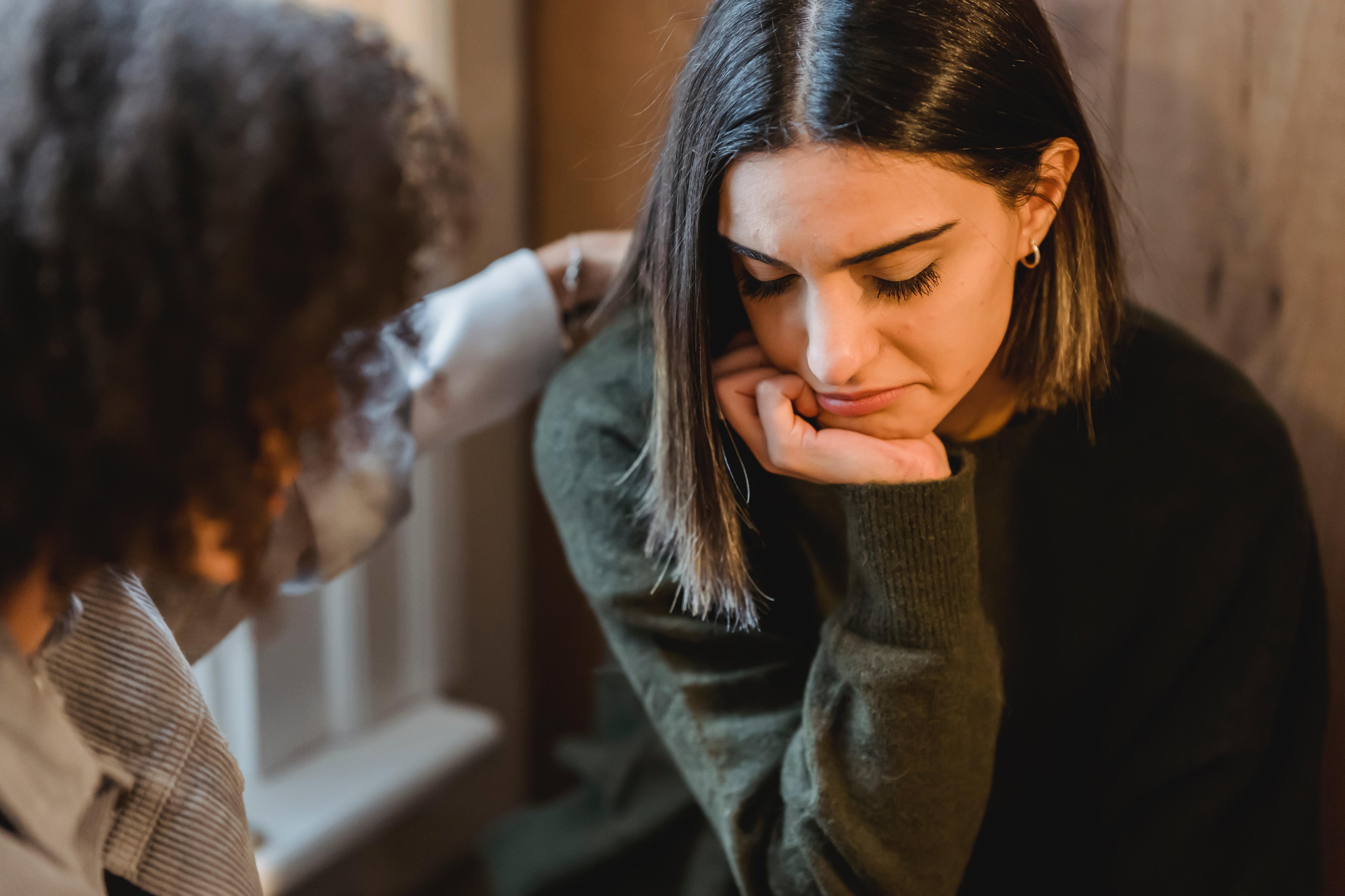 Young woman comforting another upset young woman.