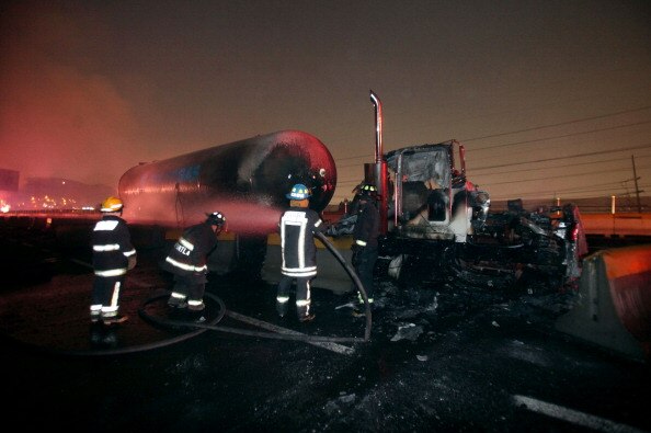 Firefighters work by a gas tanker that blew up on a highway in Ecatepec