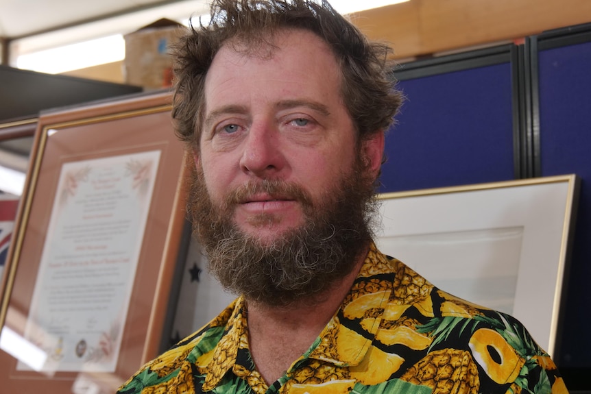 a man with facial hair wearing a pineapple patterned shirt