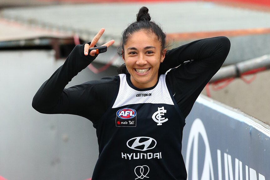 Darcy Vescio smiles and puts up the peace sign before a Carlton Blues AFLW training session 