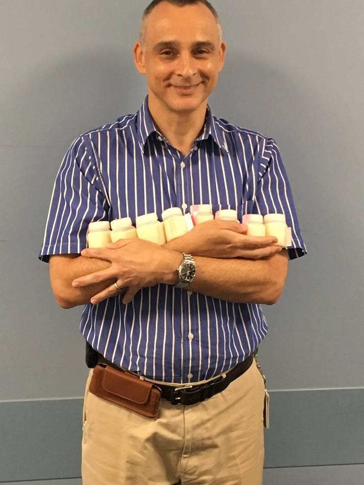 Man standing holding very small bottles of milk