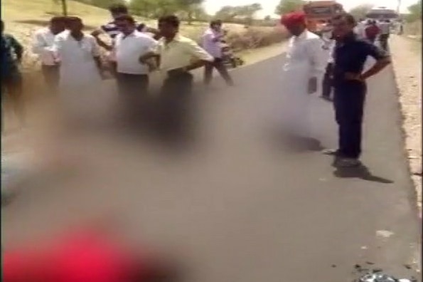 People stand around watching as a person lies on the ground after an accident