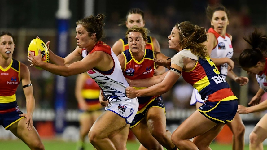 Ellie Blackburn is caught with the ball by the Crows defence.