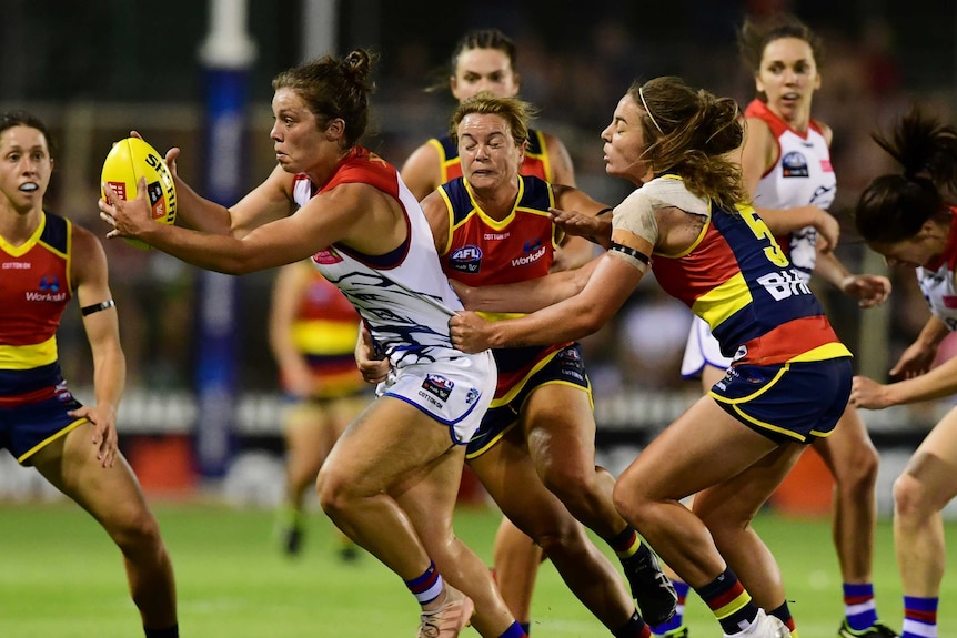 Ellie Blackburn is caught with the ball by the Crows defence.