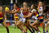 Ellie Blackburn is caught with the ball by the Crows defence.