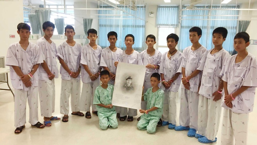 Rescued soccer team members pose with a sketch of the Thai Navy SEAL diver