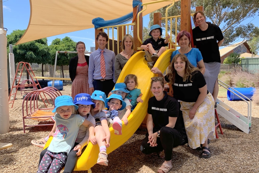 Picture of kids on a slide, with adults standing around the slide 