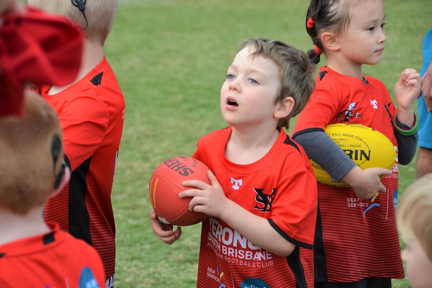 Asher O'Keeffe, 4, reading instructions at Auslan Aussie rules at Yeronga South Brisbane Devils AFL club